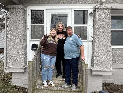 Family standing in front of home with keys