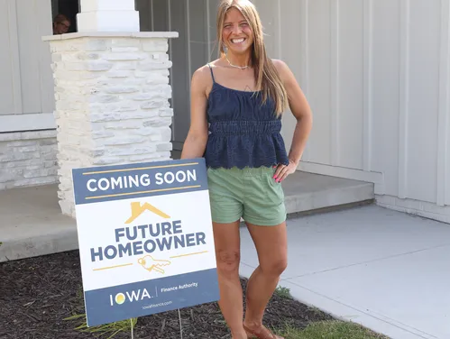 female standing in front of  sold sign