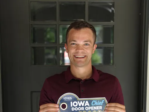 a man holding a key sign in front of a home