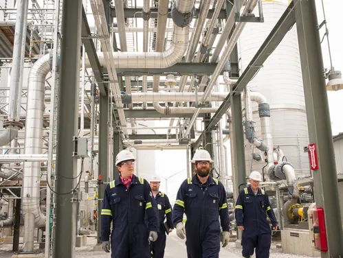 four industrial workers walking in protective gear