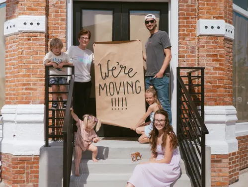 a group of people outside of a storefront holding a sign that says "we're moving in"