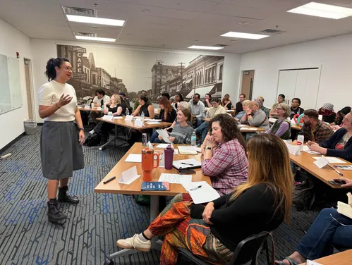a group of people in a training sitting at desks facing a standing presenter