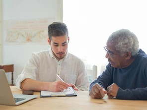 Man with laptop helping older man