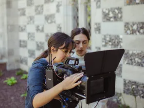 Two women working with a camera to film