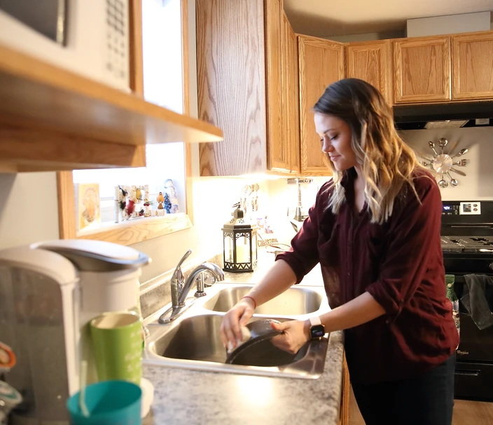 Woman washing dishes at the kitchen sink