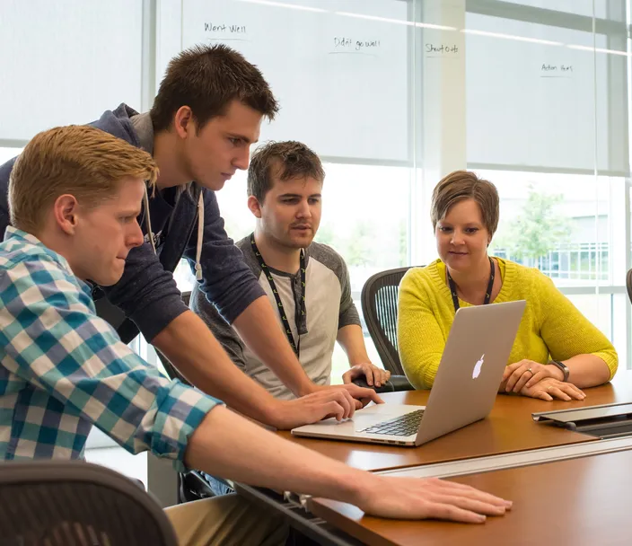 People gathered around a computer at a conference table in an office setting