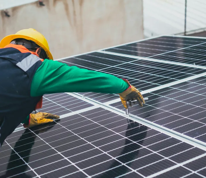 A worker leans on solar panels during a job task