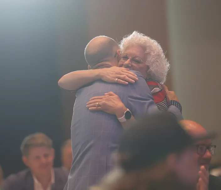 two people hugging at an awards ceremony