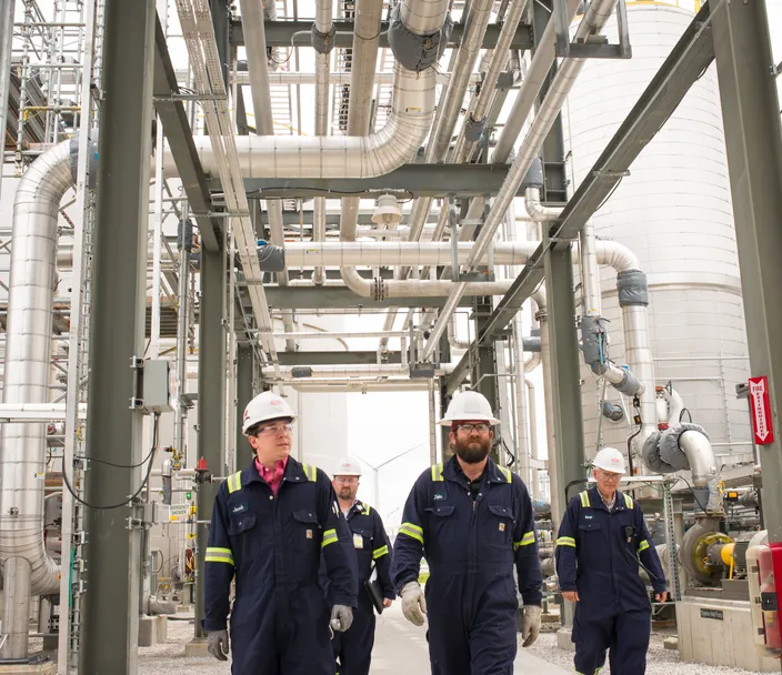 four industrial workers walking in protective gear
