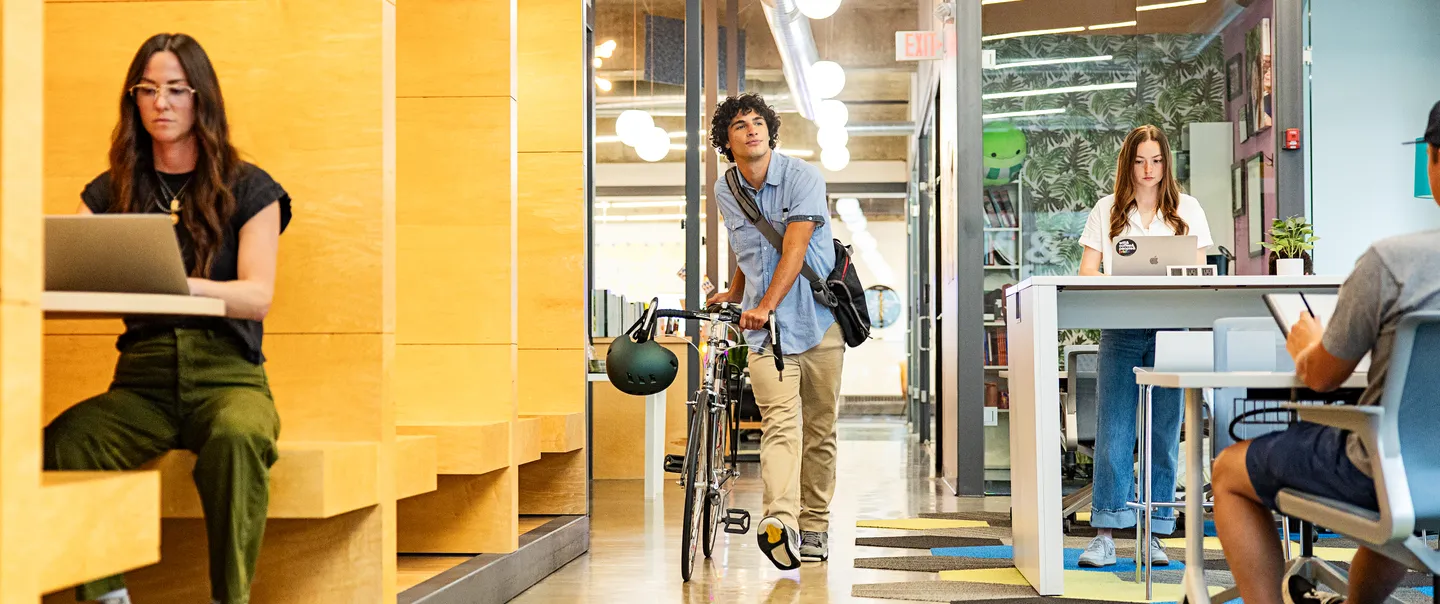 man walking with a bike through a coworking space