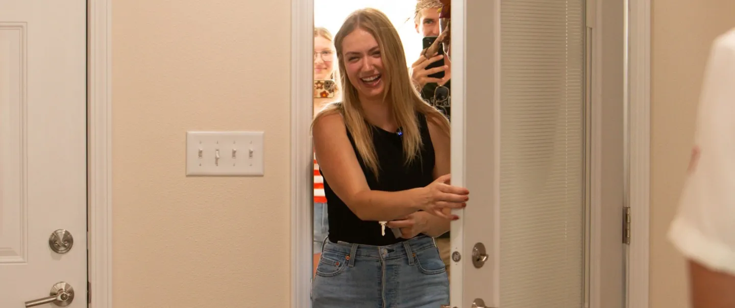 woman smiling while opening the front door of a home