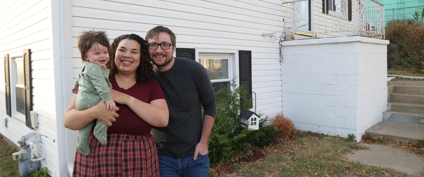 a family standing in front of a white house