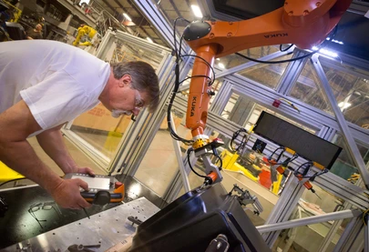 Man working in a factory with a robotic arm