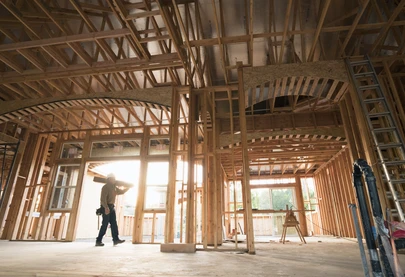 Construction worker carrying boards inside a building framing