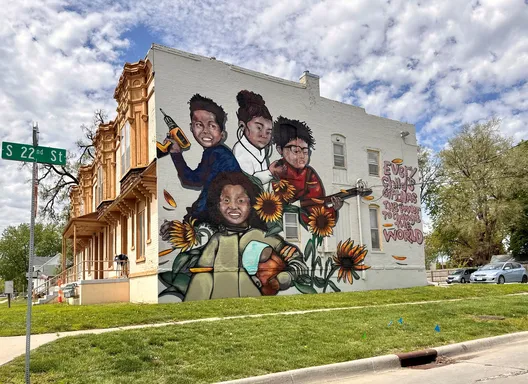 mural of four people in sunflowers on the side of a residential building