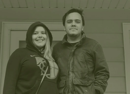 A couple standing in their porch, smiling