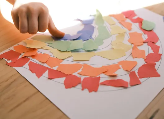 Child working with construction paper making a rainbow