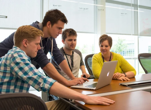 People gathered around a computer at a conference table in an office setting