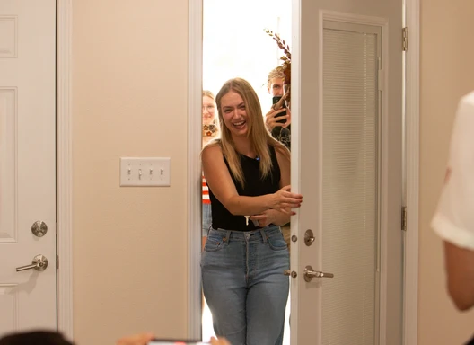 woman smiling while opening the front door of a home