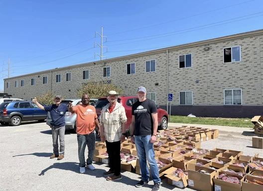 Four people standing in front of rows of boxes