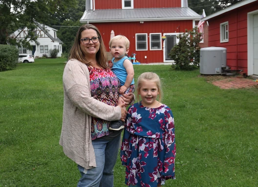 a family stands outside of their red house