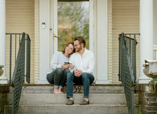 two people sitting on the front porch of a house