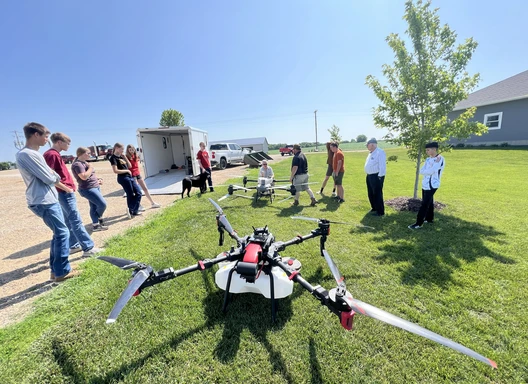 Drone team standing with a large drone on a lawn