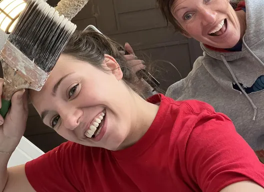 Two women with paintbrush held up.