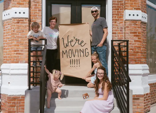 a group of people outside of a storefront holding a sign that says "we're moving in"
