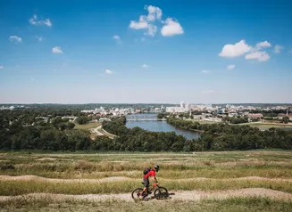 Bicyclist riding Mount Trashmore (Cedar Rapids) with river in background