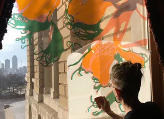 Artist applying transfer of their floral artwork to a window