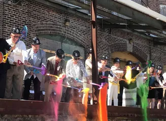 People in hard hats dumping shovels of colored powder onto the ground 