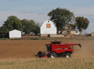 Harvesting crops with barn in the background
