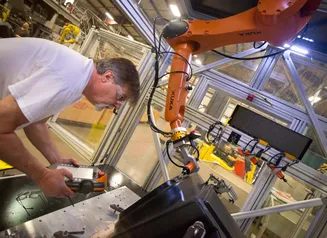 Man working in a factory with a robotic arm