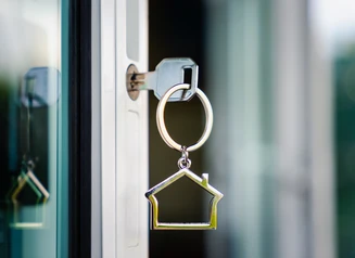 Keys in a door with a keychain shaped like a house icon