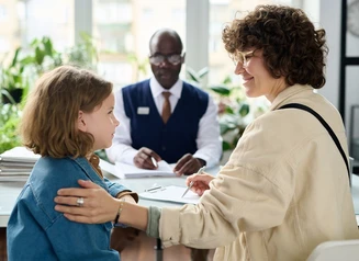 Child and adult with authority figure wearing nametag sitting at a desk