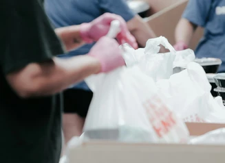 Hands bagging food from cardboard boxes