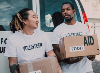 Two people in Volunteer shirts with boxes of food aid