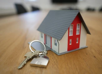 Red and white miniature house and set of keys on table
