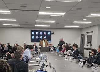 IHAF board meeting - man at podium speaking to attendees sitting around table