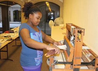 Girl working at a weaving loom