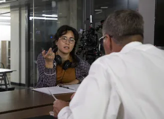 Person wearing headphones having a conversation with another person with a binder in front of them