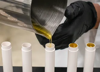 Gloved hands filling lip balm containers