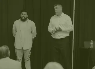 Two businessmen talking in front of an audience