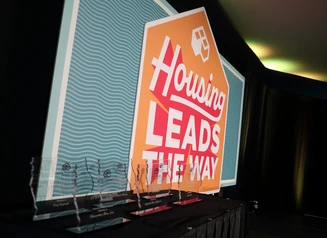 Trophies in front of Housing Leads the Way sign