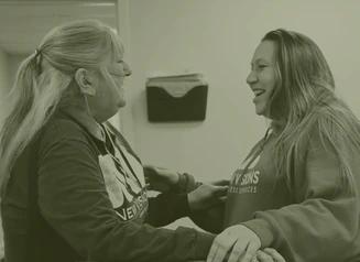 Two ladies hugging in office setting