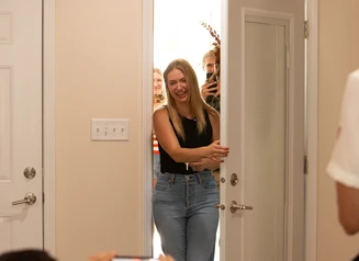 woman smiling while opening the front door of a home
