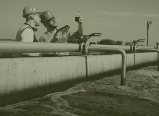 Two technicians in hard hats looking at water sample