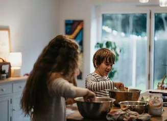 two kids in kitchen mixing ingredients in bowls
