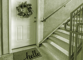 Apartment door with wreath and mat next to step